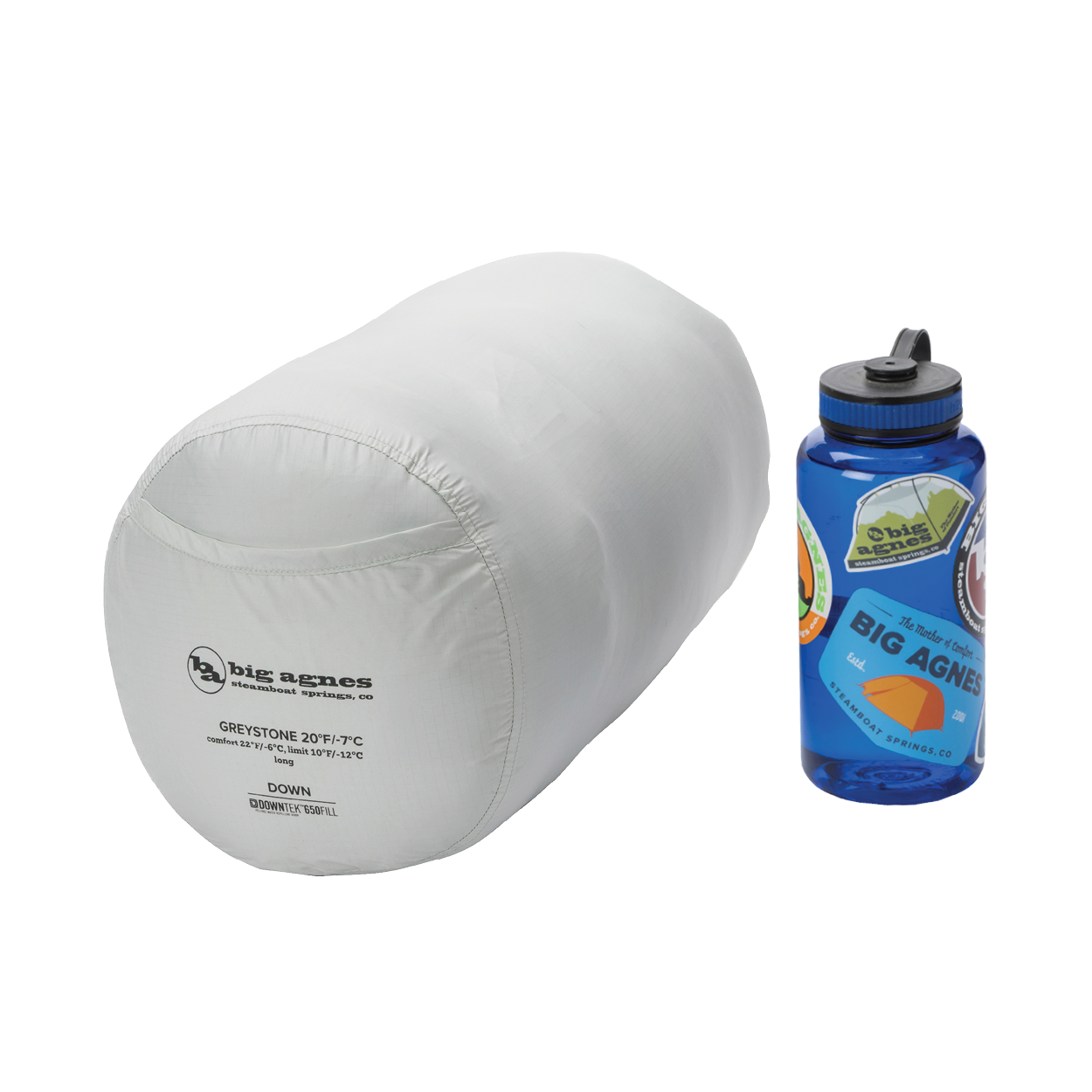 The Big Agnes Returns Greystone 20° sleeping bag sits beside a blue, sticker-covered Nalgene, highlighting its compact size—ideal for backpacking trips.
