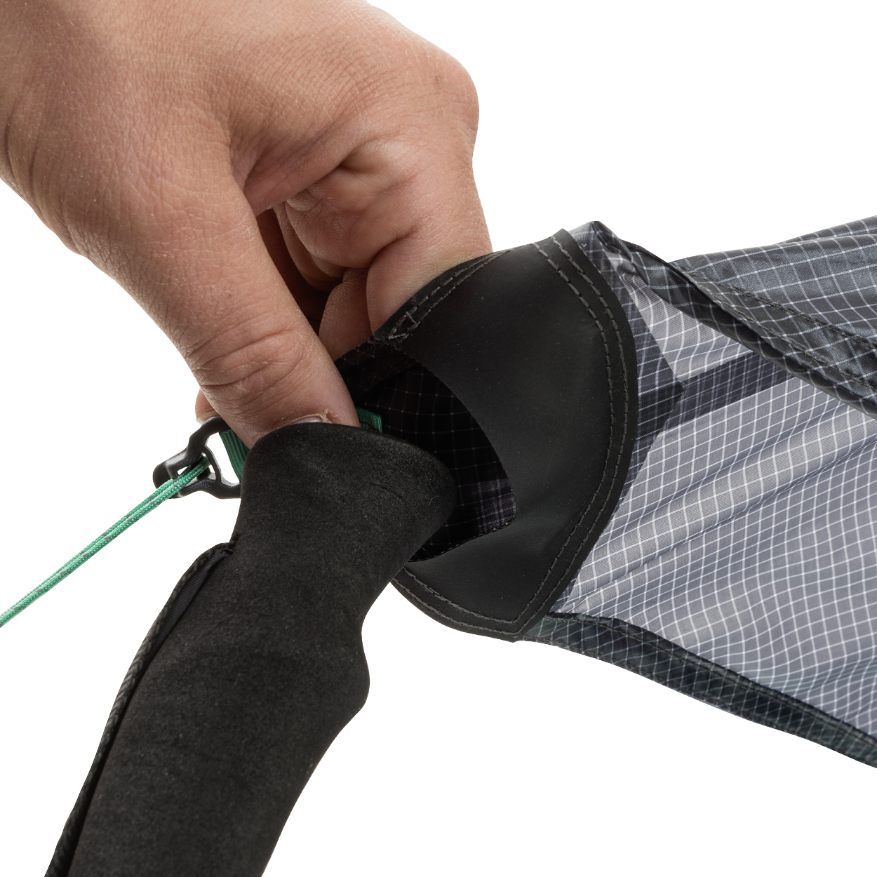 A close-up of a hand tying a green string to the end of the black and gray String Ridge VST 1.5 by Big Agnes, highlighting its detailed fabric and handle—ideal for assembling ultralight shelters or VST tents on your outdoor trips.
