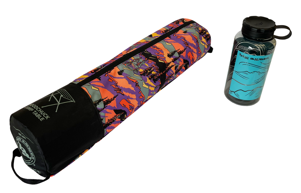 A colorful, patterned carrying case with Big Agnes Returns branding lies next to a clear water bottle with a blue mountain design and black lid—both perfect companions for your Woodchuck Camp Table - Alpenglow adventures.